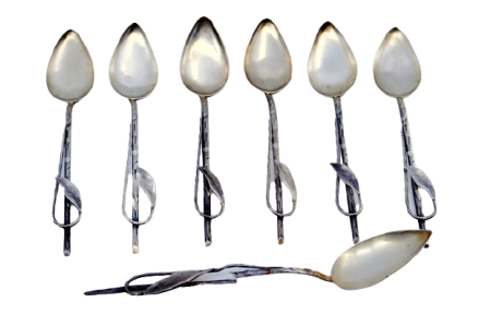 Conjunto de seis colheres de café e pá de açúcar em prata com relevos e aplicação de folhas nos cabos.